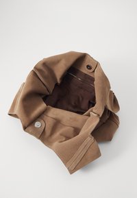 Sac en suède marron avec une texture douce, doté d'une fermeture à bouton et d'une poche zippée à l'intérieur, présentant une doublure marron contrastante.