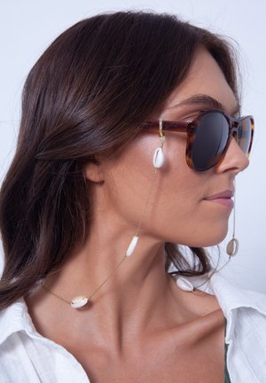 Tortoiseshell sunglasses with dark lenses, connected by a gold chain featuring white and beige shell accents.