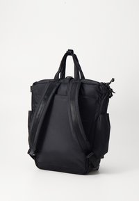 Sac à dos noir en tissu durable, avec des bretelles rembourrées, fermeture éclair et poches latérales pour le rangement. Forme carrée avec un design minimaliste.