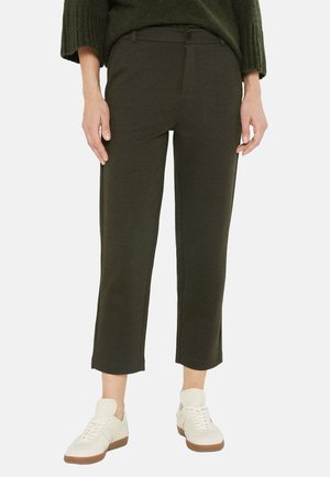 Dunkelgrüne, strukturierte Hose mit schmaler Passform, umgeschlagenem Saum und vorderen Taschen. Kombiniert mit hellen Sneakers für einen lässigen Look.