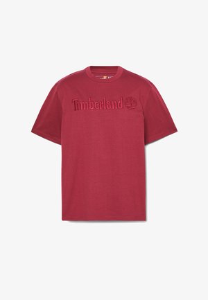 T-shirt en coton rouge avec un logo "Timberland" en relief et un emblème d'arbre sur le devant, avec un col rond classique et des manches courtes.