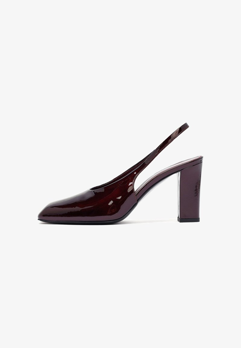 Escarpin slingback en cuir verni bordeaux avec un bout pointu et un talon épais, présentant un design à découpes sur les côtés et une finition brillante.