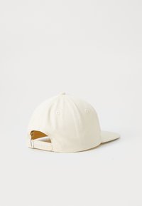 Beige baseball cap with a flat brim, made of cotton fabric. Features a adjustable snapback closure and ventilation eyelets.