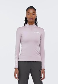 Maglietta atletica a maniche lunghe rosa chiaro con colletto a mezza zip e logo bianco "TERREX" sul petto e sulla manica. Tessuto liscio e elastico.