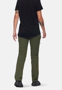 Olijfgroene outdoorbroek met een slim fit, verstevigde panelen en logodetail. Gecombineerd met een zwart T-shirt met korte mouwen en zwarte schoenen.