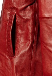 Rote Lederjacke mit weicher Textur, sichtbaren Nähten und einer Seitentasche. Der Glanz betont die satte Farbe und die Qualität des Materials.