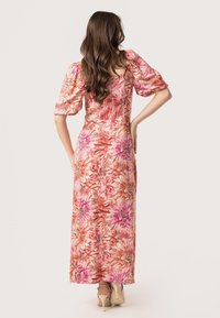 Robe maxi à imprimé floral avec des teintes roses et corail, manches bouffantes, corsage ajusté et jupe fluide, fabriquée en tissu léger.