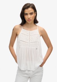 Witte mouwloze blouse met een kantontwerp, ingewikkelde stikdetails en een ontspannen pasvorm, met een ronde halslijn en zijzakken.