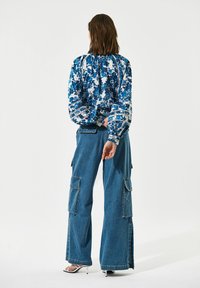Vloeiende blauwe bloemenblouse met pofmouwen, gecombineerd met wijde denim cargobroek met zijzakken en een ontspannen pasvorm.