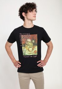 Černé bavlněné tričko s potiskem květinové vázy a textem v světle růžové barvě, s kulatým výstřihem a krátkými rukávy.