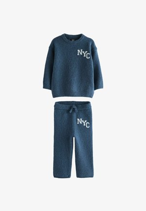 Modra pletena jakna in hlače s vezenjem "NYC" v beli barvi. Mehka tekstura in sproščen kroj. Jakna ima okroglo ovratnico in dolge rokave.