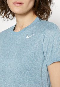Jasnoniebieska koszulka Nike wykonana z miękkiego, fakturowanego materiału, z okrągłym dekoltem i białym logo Swoosh na lewej piersi.