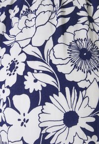 Marinblått tyg med ett vitt blommönster som innehåller olika blommor, blad och detaljerade konturer, vilket skapar en kontrasterande design.