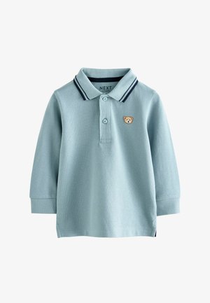 Ljusblå pikétröja med långa ärmar, krage, marinblå randiga detaljer och en björnmotiv broderat på bröstet.