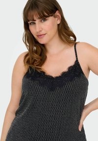 Top de tirantes negro con encaje en el escote. Patrón texturizado con acentos plateados. Tirantes finos ajustables, corte holgado, tela suave.