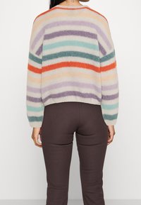 Farverig stribet sweater med en cropped design; har grønne, lilla, orange og fløde farver; lavet af fuzzy strikmateriale.