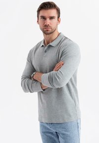 Šedá polokošile s dlouhým rukávem vyrobená z bavlněné směsi, se klasickým límcem, dvěma knoflíky a mírně zúženým střihem.