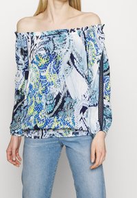 Blusa off-the-shoulder con un motivo astratto colorato in blu, verde e bianco; presenta maniche lunghe con polsini elasticizzati e accenti testurizzati.