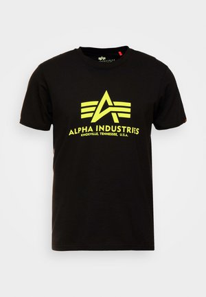 T-shirt in cotone nero con un grande logo giallo caratterizzato da una "A" stilizzata e tre strisce orizzontali. Collo giroclassico con maniche corte.