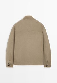 Beige langærmet jakke med krave, knappede manchetter og synlige syningsdetaljer, vist bagfra på en hvid baggrund.