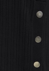 Svart ribbat tyg med silverfärgade metallknappar längs ena sidan. Texturen är slät med vertikala spår. Knapparna är runda och metalliska.