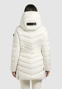 Witte pufferjas met chevron-quilt, ceintuur in de taille, hoge kraag en zwart logo op de capuchon; heeft lange mouwen en een ritssluiting aan de zijkant.