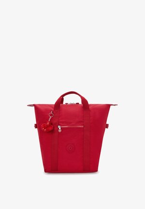 Sac cabas rouge avec deux poignées supérieures, poche zippée à l'avant et un petit porte-clés singe rouge attaché à une des poignées.