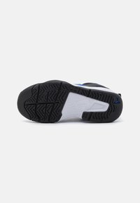 Černobílá podrážka sportovní obuvi s texturovaným černým gumovým povrchem, obsahující modrý akcent a výrazným vzorem protiskluzu pro lepší přilnavost.