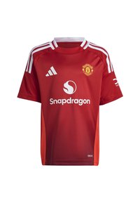 Maillot de football rouge en tissu léger, avec des accents blancs, des manches courtes, un col rond et le logo de Manchester United. Nom de la marque visible.