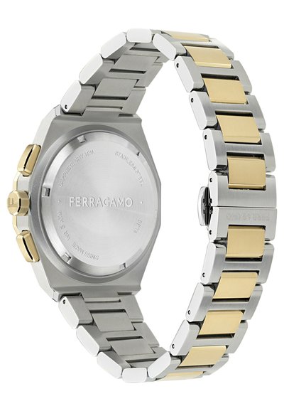 Reloj de acero inoxidable plateado con una caja octogonal, acentos dorados en la pulsera y un acabado suave y pulido. La parte trasera tiene detalles grabados.
