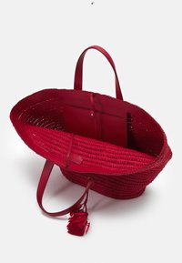 Czerwona torba na ramię pleciona, z skórzanymi uchwytami, z teksturowanym wnętrzem, małą kieszonką i dekoracyjnym akcentem w postaci chwosta.