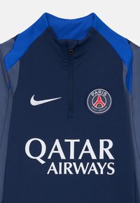 Pull-over de sport bleu marine avec col montant, zip quart, panneaux latéraux gris, logo "QATAR AIRWAYS" blanc et patch rond "PARIS" sur la poitrine.