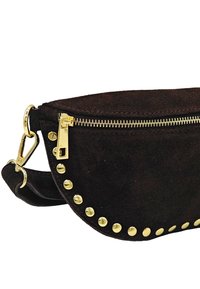 Sac en suède marron au design courbé, avec une fermeture éclair dorée et des accents cloutés le long du bord. Il dispose d'une bandoulière détachable et d'une tirette de fermeture éclair.