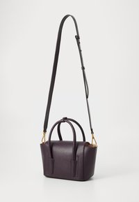 Sac bandoulière en cuir violet avec une finition texturée, double poignée haute et une sangle détachable et ajustable. Accents en matériel doré visibles.