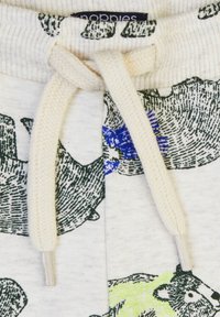 Tkanina w kolorze kremowym z wzorem misia w odcieniach zieleni, niebieskiego i czarnego, z dzianinowym paskiem w talii oraz beżowym sznurkiem do regulacji z przodu.