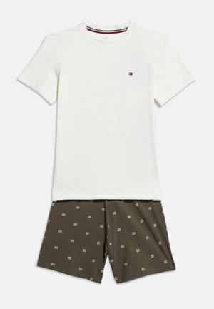 Fehér, rövid ujjú, kerek nyakú póló sötétzöld rövidnadrággal, melyen apró, ismétlődő fehér téglalapminták találhatók.