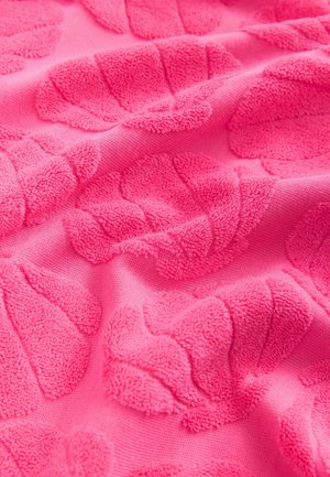 Svijetlo ružičasta izgleda tkanina sa uzorcima izbočenih listova. Materijal ima mekan, plišan osjećaj, stvarajući taktilnu površinu.