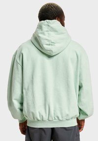 Felpa oversize verde menta con un ampio cappuccio regolabile, polsini e orlo a coste. Tessuto morbido e vestibilità rilassata per il massimo comfort.