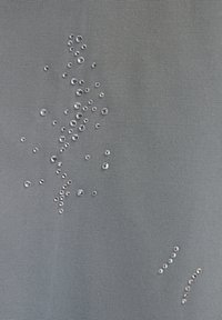 Grå stof med mange klare vanddråber, der er spredt uregelmæssigt, varierende i størrelse, og fremhæver tekstur og vandafvisende egenskaber.