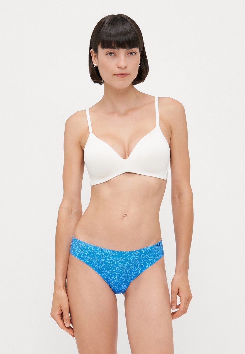 Witte gevoerde bh met dunne bandjes, gecombineerd met een blauwe bikini onderkant met patroon, gekenmerkt door een gladde textuur en een elastische tailleband.
