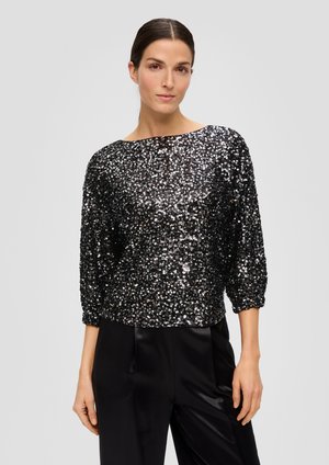 Zwarte sequined top met driekwartmouwen, bootnek en een relaxte pasvorm, aangevuld met zwarte satijnen broek.