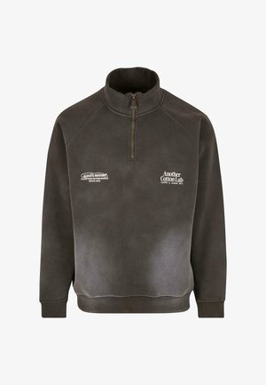 Ciemnoszary polarowy pulower z półzamkiem przy kołnierzu. Posiada dwa nadrukowane logo na piersi. Miękka tekstura i standardowy krój. Ribrowane mankiety i dół.