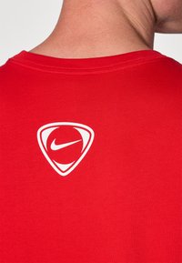 Rode katoenen T-shirt met een ronde halslijn, met op de achterkant een witte Nike-logo in een driehoekige omlijning. Soepele textuur.