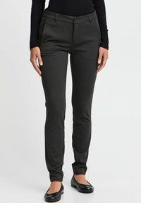 Pantaloni neri su misura realizzati in un tessuto liscio e elasticizzato, caratterizzati da un design aderente, tasche laterali e chiusura con bottone.