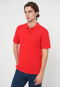 Czerwona koszulka polo wykonana z bawełnianej mieszanki tkanin, z klasycznym kołnierzykiem, krótkimi rękawami oraz subtelnym logo na lewej piersi.