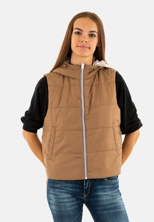 Chaleco acolchado marrón con capucha, que presenta un cierre frontal y bolsillos laterales, usado sobre una camiseta de manga larga negra. Textura suave, diseño ligeramente acolchado.