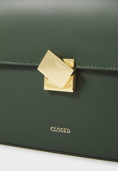 Vihreä nahkainen käsilaukku, jossa on teksturoidun pinnan viimeistely. Laukussa on geometrinen kultainen solki ja kohokuvioitu "CLOSED"-brändäys kullalla.