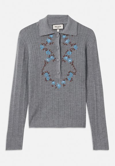 Pilkas raštuotas megztinis su apykakle, su sagomis priekiniame šone ir išsiuvinėti mėlyni gėlės ant krūtinės. Strukturizuota medžiaga ir prigludęs stilius.