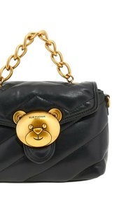 Borsa a mano in pelle nera con texture trapuntata, un fermo a forma di orso dorato e una tracolla chunky in oro.