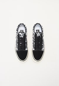 Mustavalkoiset tennarit, joissa on kuvioitu tekstiilipäällinen, nupukkinahkainen varvassuoja, mustat nauhat ja valkoinen kumipohja.